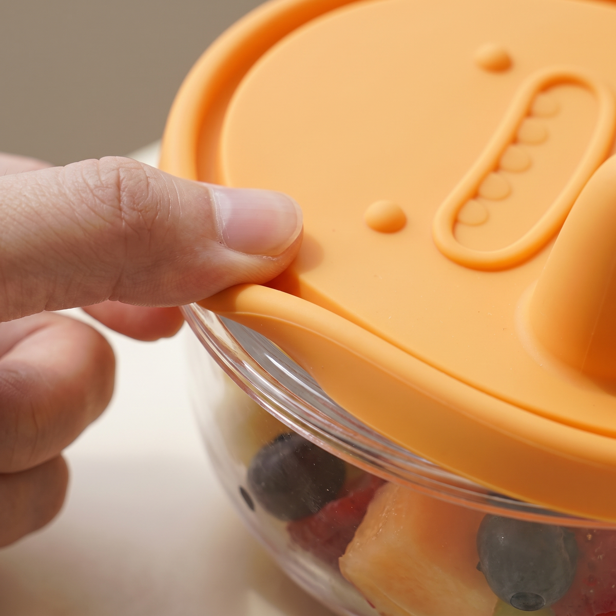 Close-up of the flexible silicone lid being pressed onto the rim of the snack pot