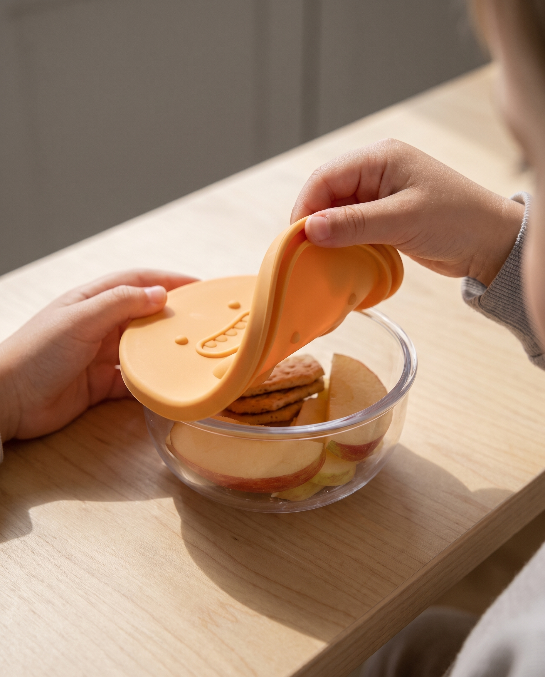 A child's hands lifting the flexible silicone lid off the snack pot